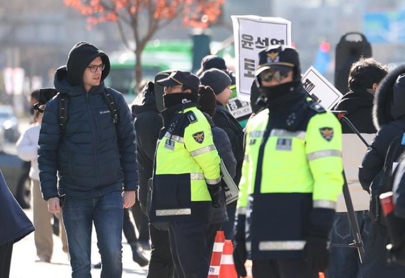 A man passes by protestors in Gwanghwamun Square, Seoul, Wednesday, against President Yoon Suk Yeol's declaration of martial law the day before.