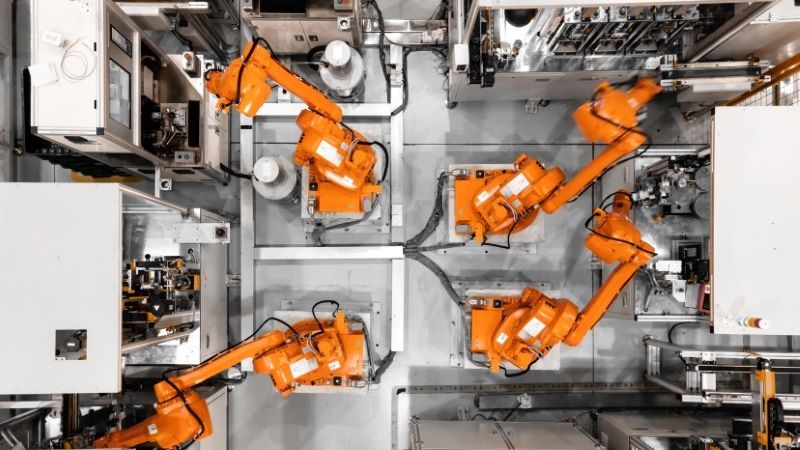 Orange industrial robot arms in factory setup