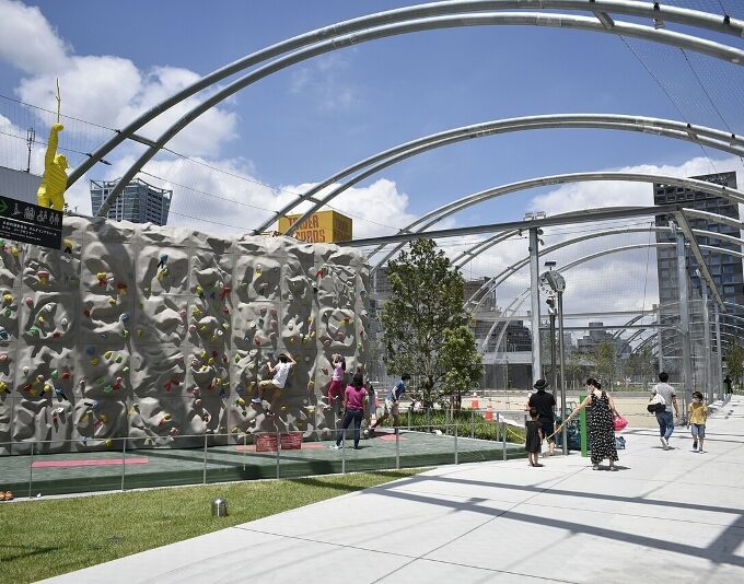 Busy urban public plaza in osaka with many people relaxing on grass